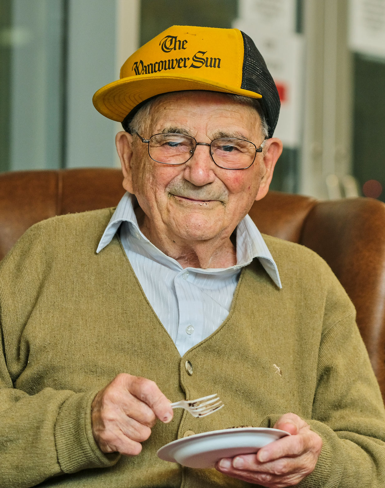 elderly man sitting down smiles and enjoys cake