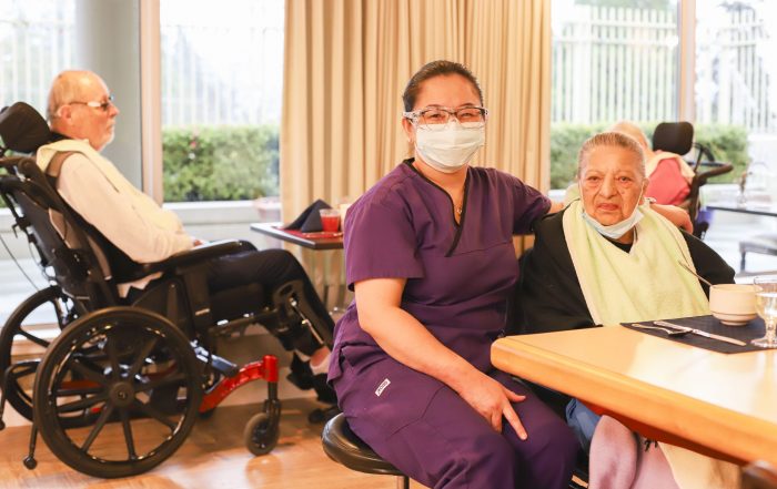 nurse provides care to senior woman eating food at care home