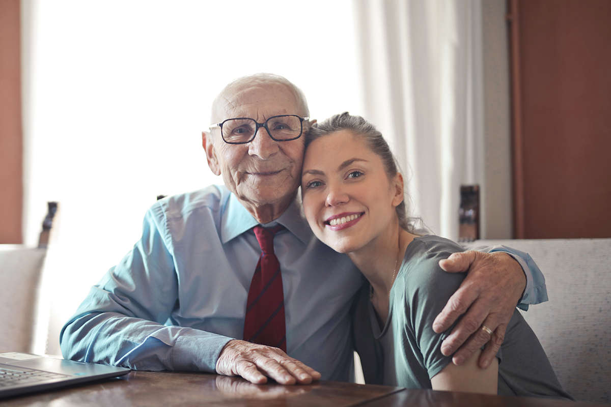 Senior man smiles as he hugs his daughter