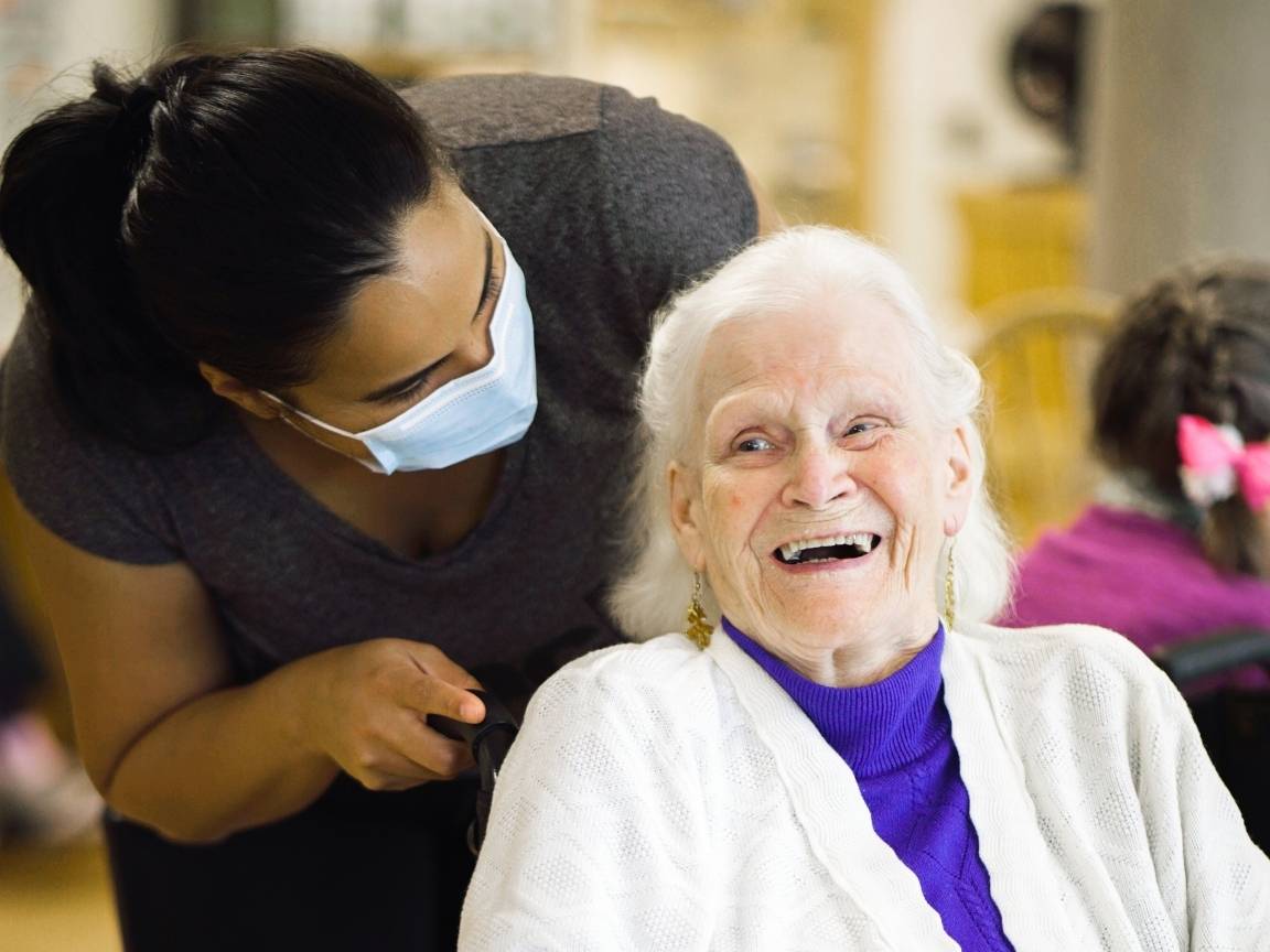 an old lady smiling happily receiving personal care services from a nurse