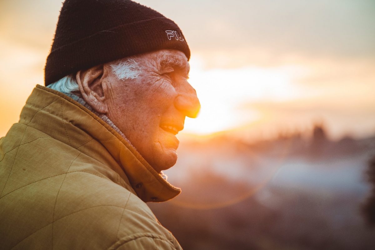 smiling senior man sitting outside watching the sunset