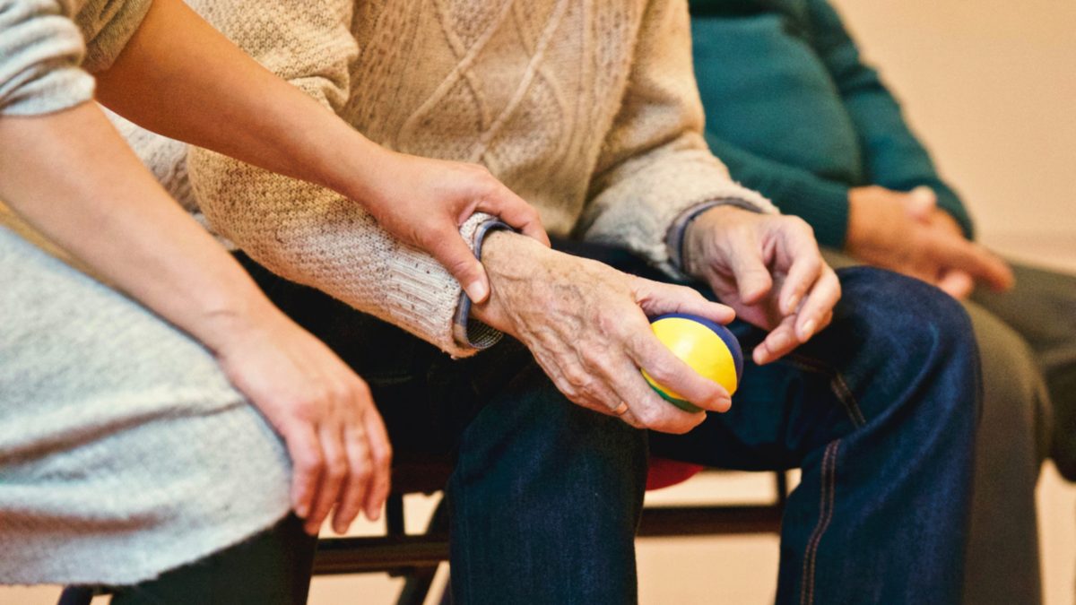 woman holds hand of elder man sitting down