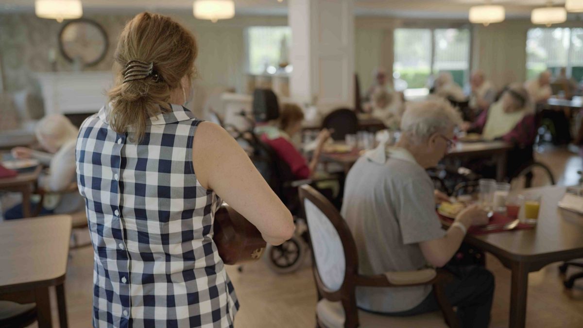 woman playing music for residents eating diner at lynn valley care centre