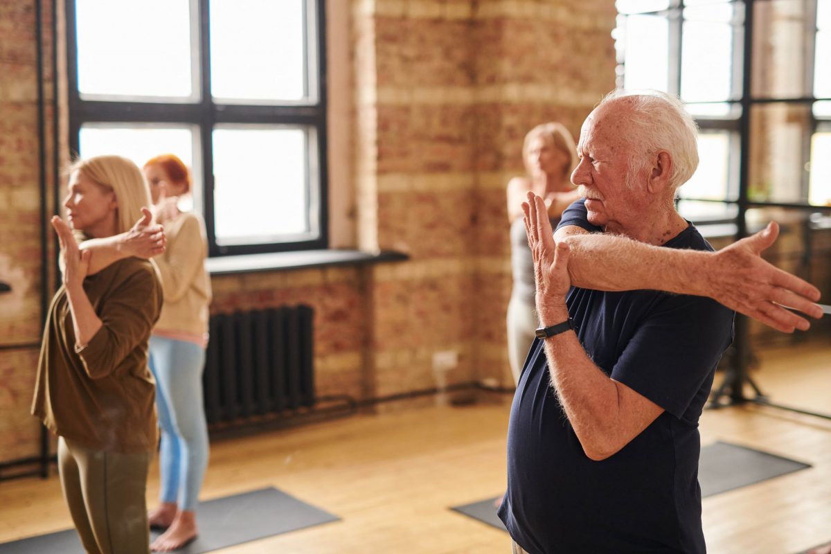 elderly man doing yoga practicing self care for seniors