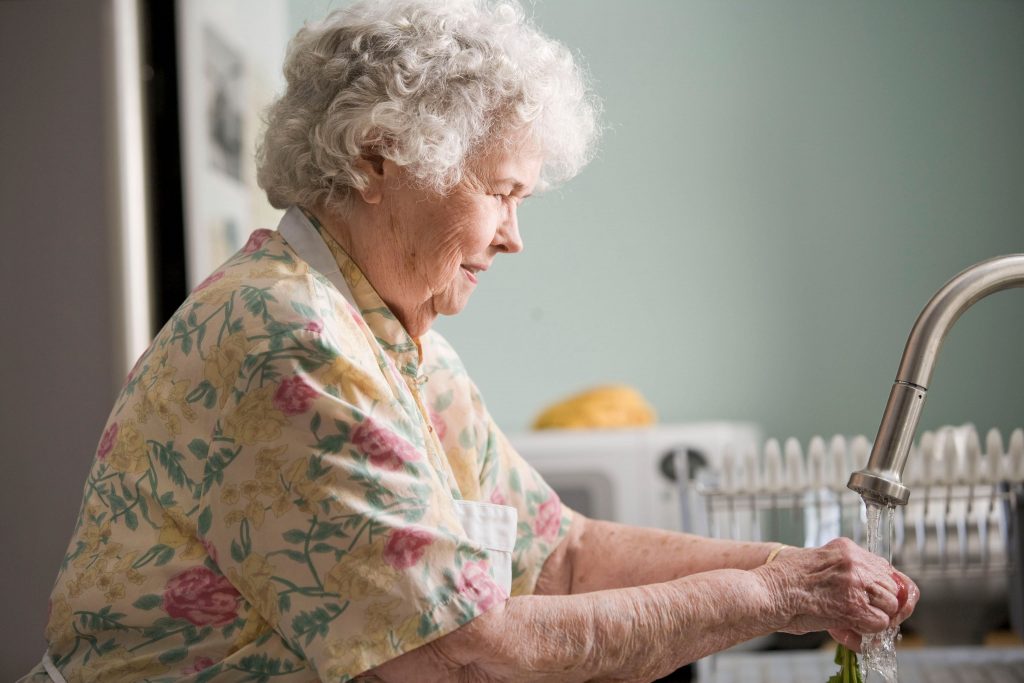 side profile of elderly woman washing hands in sink