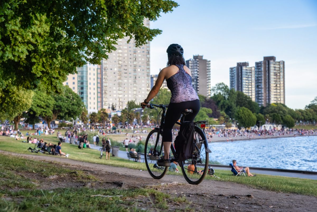 Adventurous White Caucasian Adult Woman riding a road bicycle in Stanley Park. A Fun Attractions in Vancouver BC.