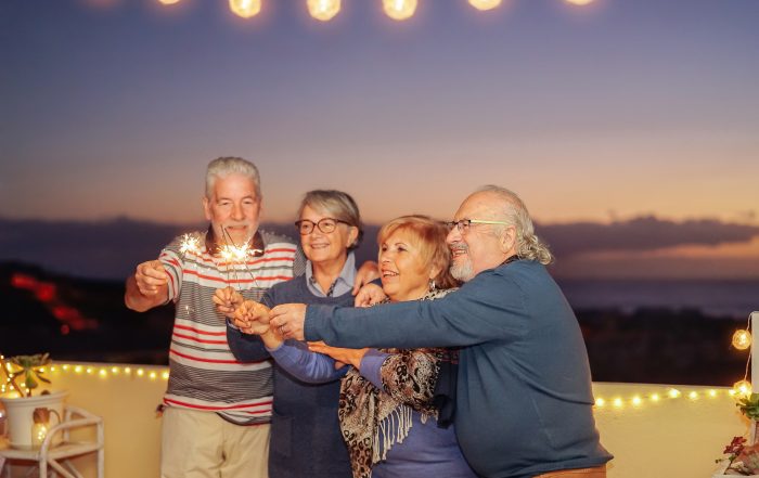 Group of happy seniors holding sparklers during a festive evening, showcasing the joy and camaraderie often experienced on Canadian bus tours for seniors.