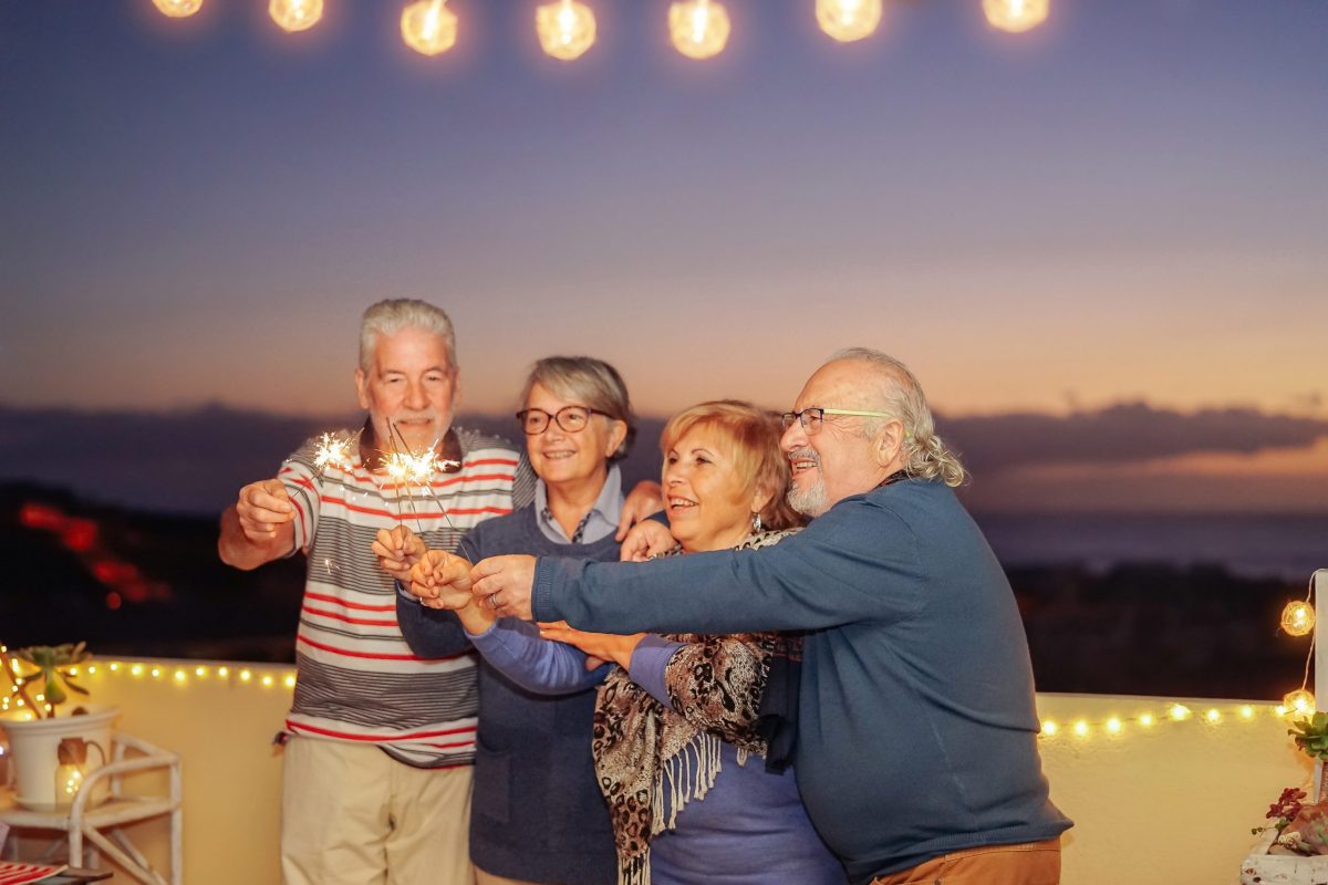 Group of happy seniors holding sparklers during a festive evening, showcasing the joy and camaraderie often experienced on Canadian bus tours for seniors.